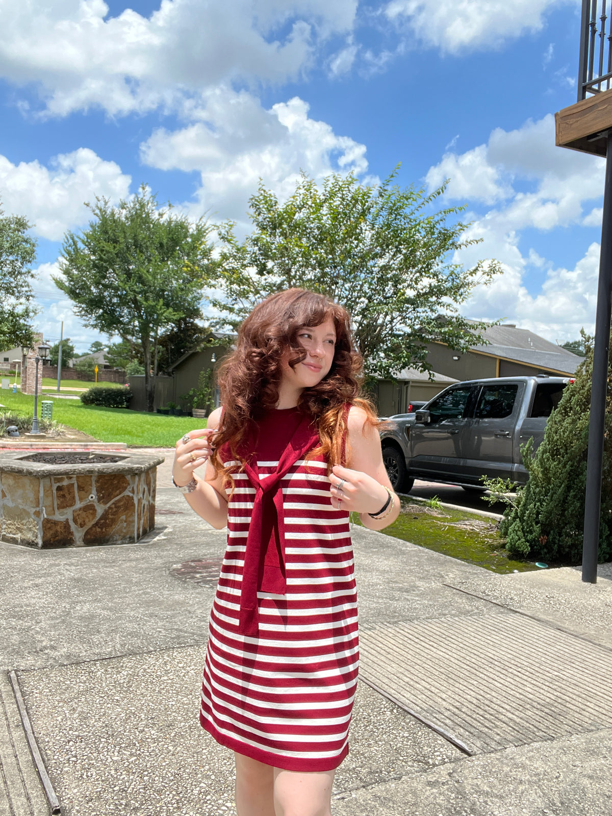 Person wearing a red and white striped dress standing outdoors on a sunny day.