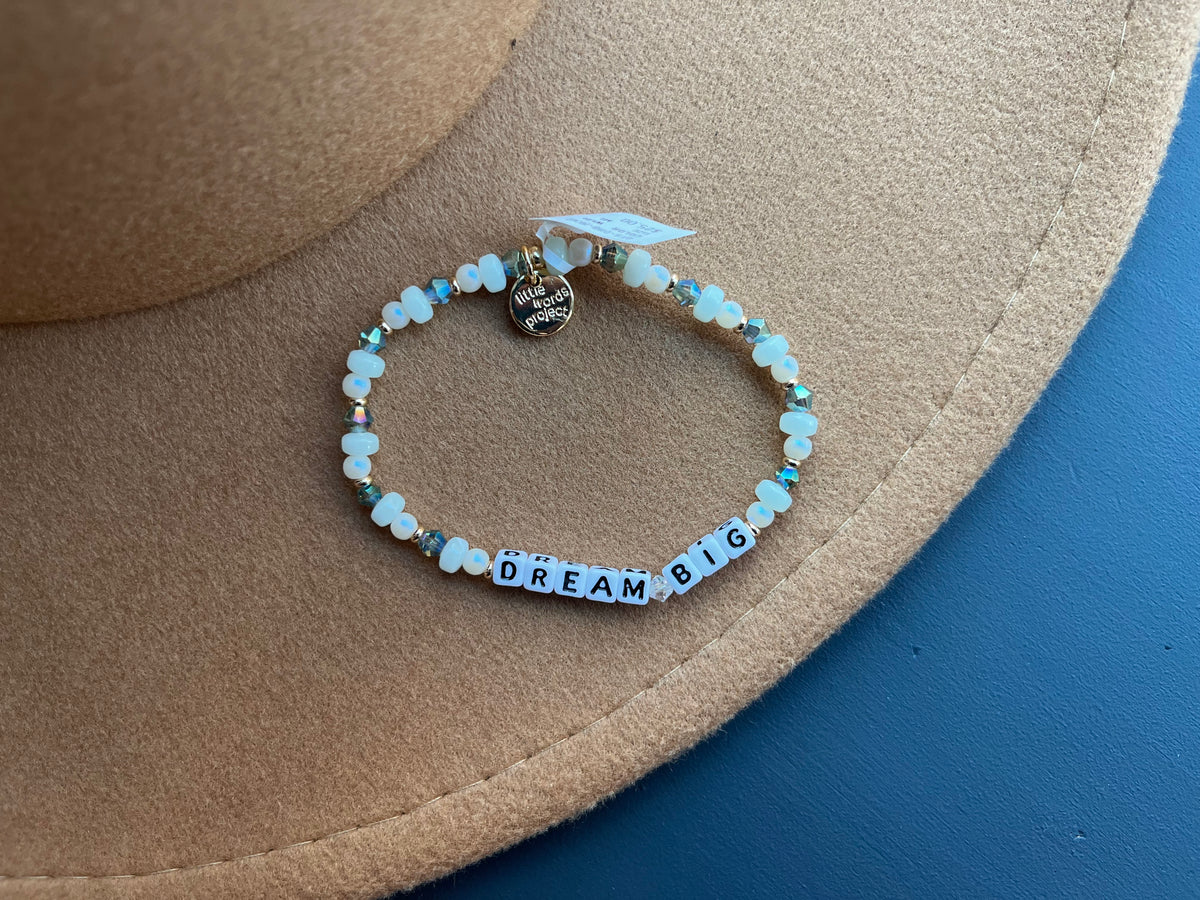 Bracelet with 'Dream Big' message on a beige hat against a blue background